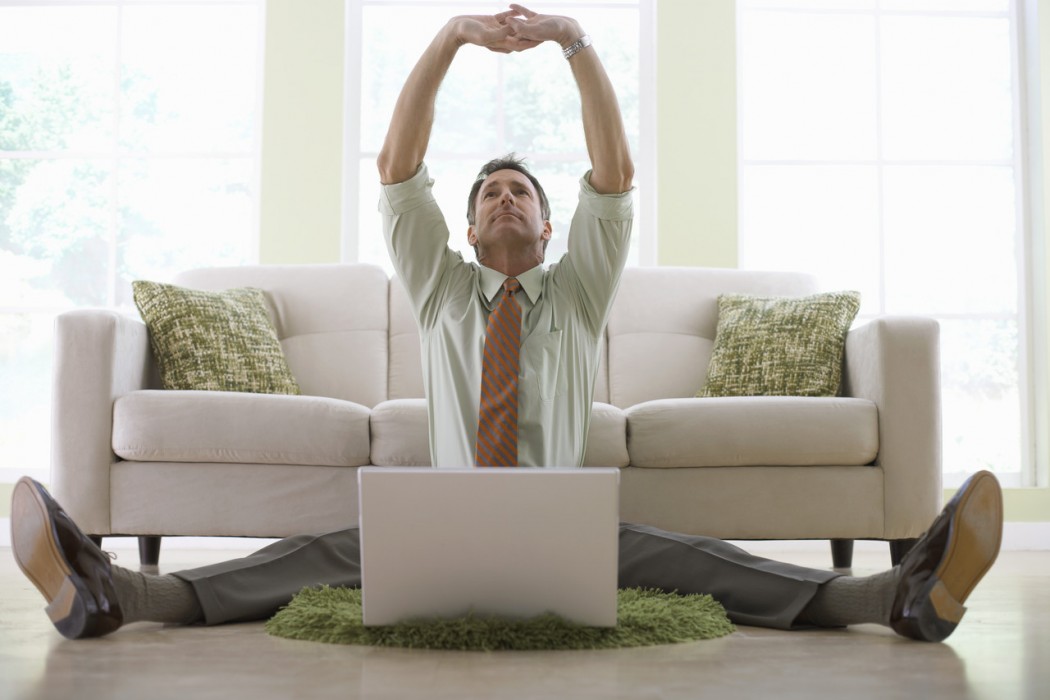 Businessman Stretching While Working on His Laptop